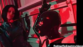 A girl in rubberdoll BDSM theme is pleasured by busty latex dominatrix and bound in latex